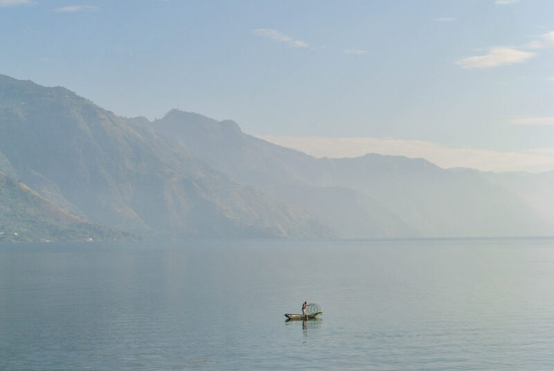 a fisherman on the water of lake Atitlan, as seen from the dock at San Pedro la Laguna