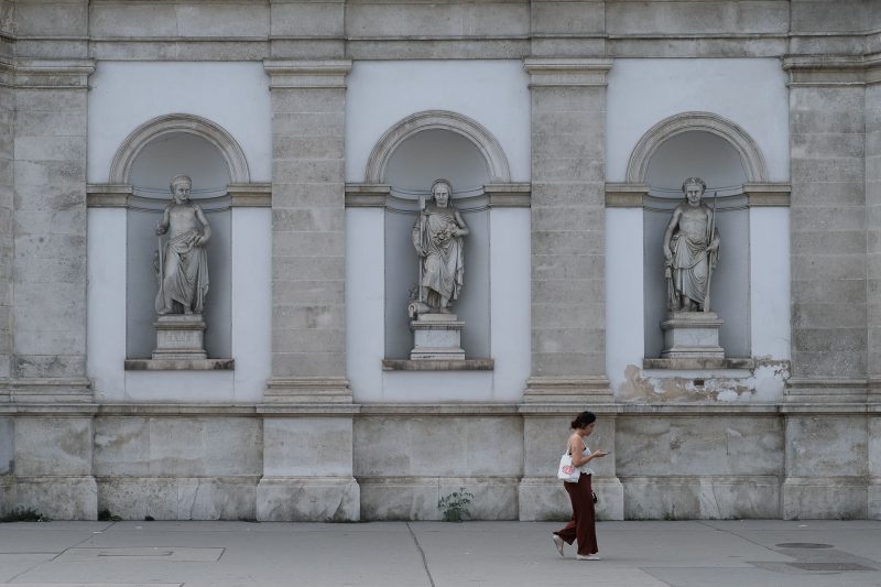 A woman walking past statues in Central Vienna